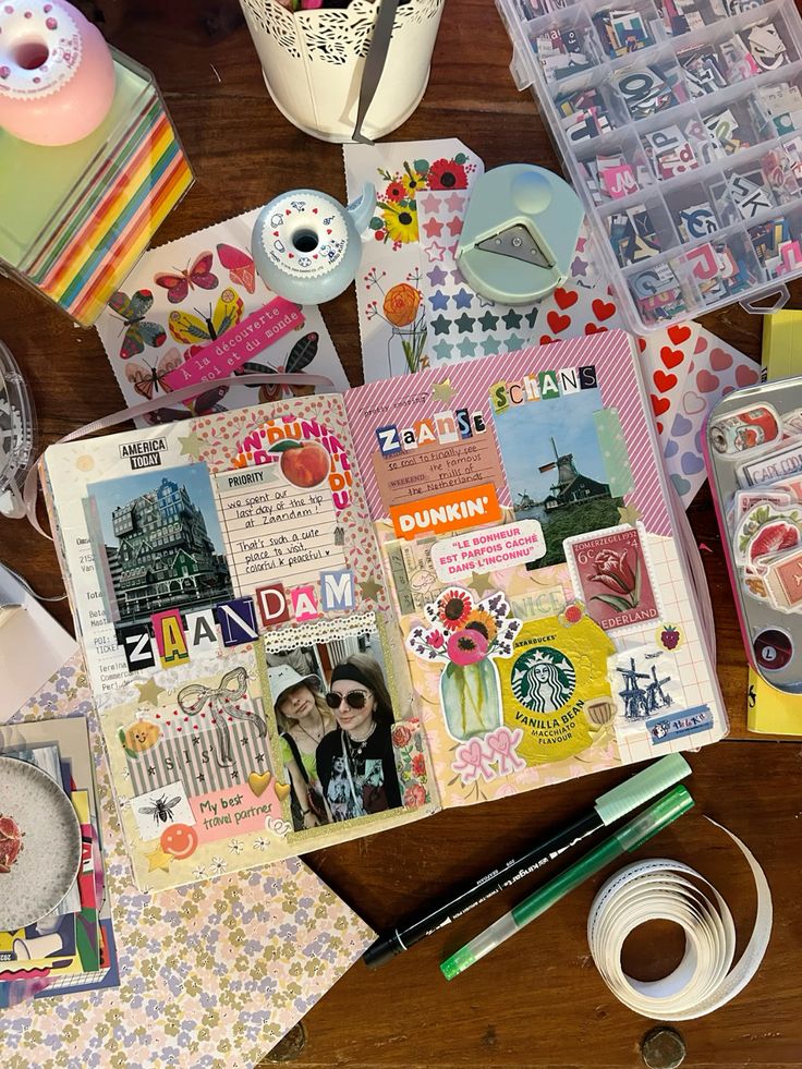 Scrapbook journal with travel memories, photos, and colorful stickers on a wooden table with craft supplies.