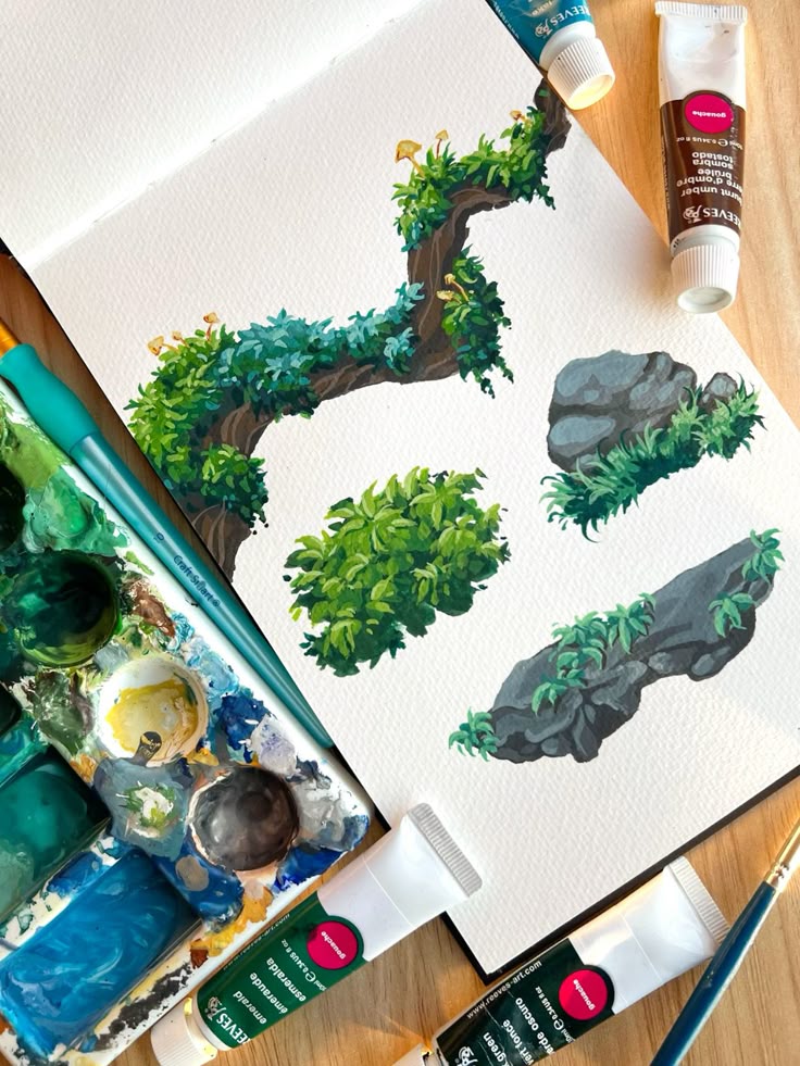 Artistic painting of greenery and rocks using gouache paints with paint tubes and palette in view.