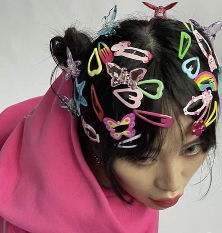 Person wearing colorful butterfly clips and a bright pink hoodie, showcasing a creative hair accessory style.