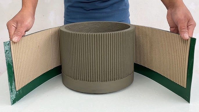 Person handling a concrete mold wrapped in flexible cardboard for crafting projects.