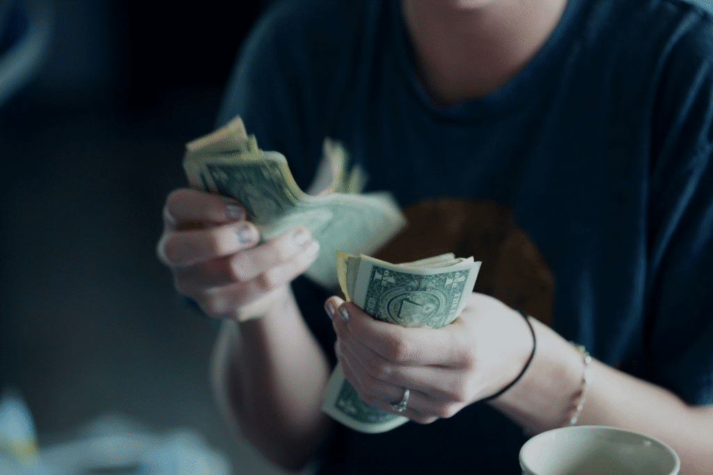 image Person counting dollar bills, focusing on hands and money, emphasizing budgeting and financial management. | Sky Rye Design Person counting dollar bills, focusing on hands and money, emphasizing budgeting and financial management.