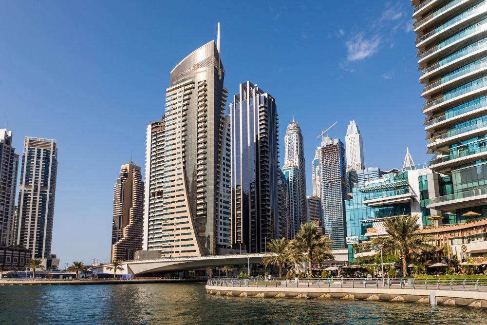 Modern skyscrapers along the waterfront in Dubai Marina with clear blue skies.