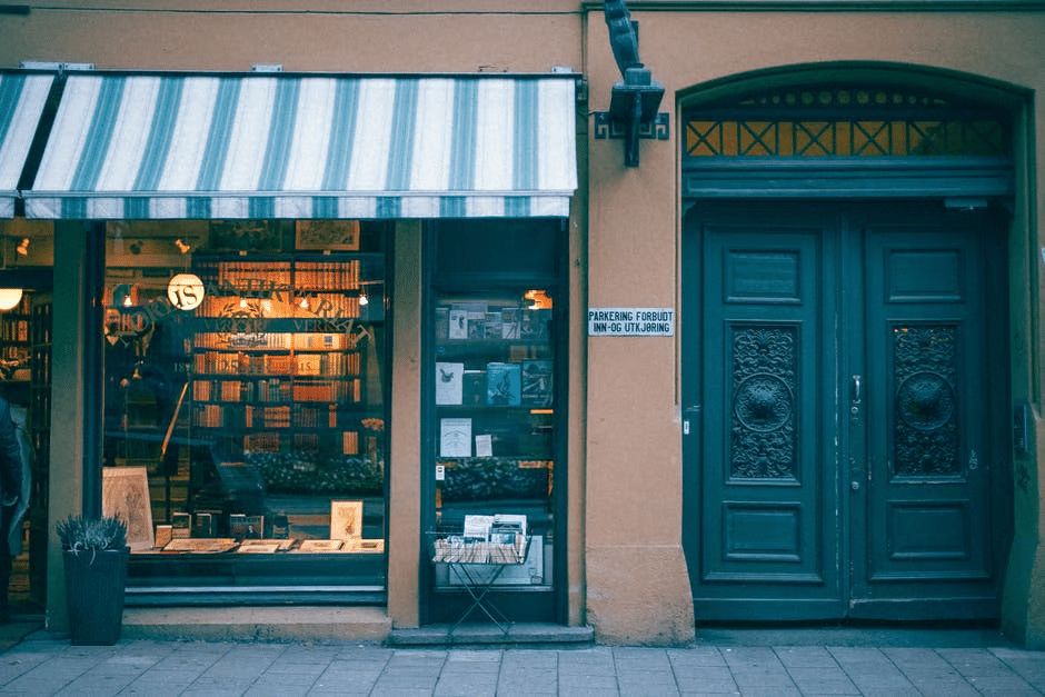 image2 Cozy bookstore with a striped awning next to a large wooden door on a city street. | Sky Rye Design Cozy bookstore with a striped awning next to a large wooden door on a city street.