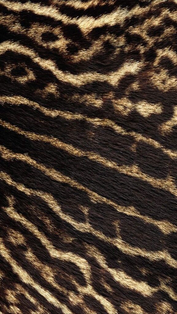 Close-up of animal fur with dark and light brown wavy patterns, resembling a leopard print texture.