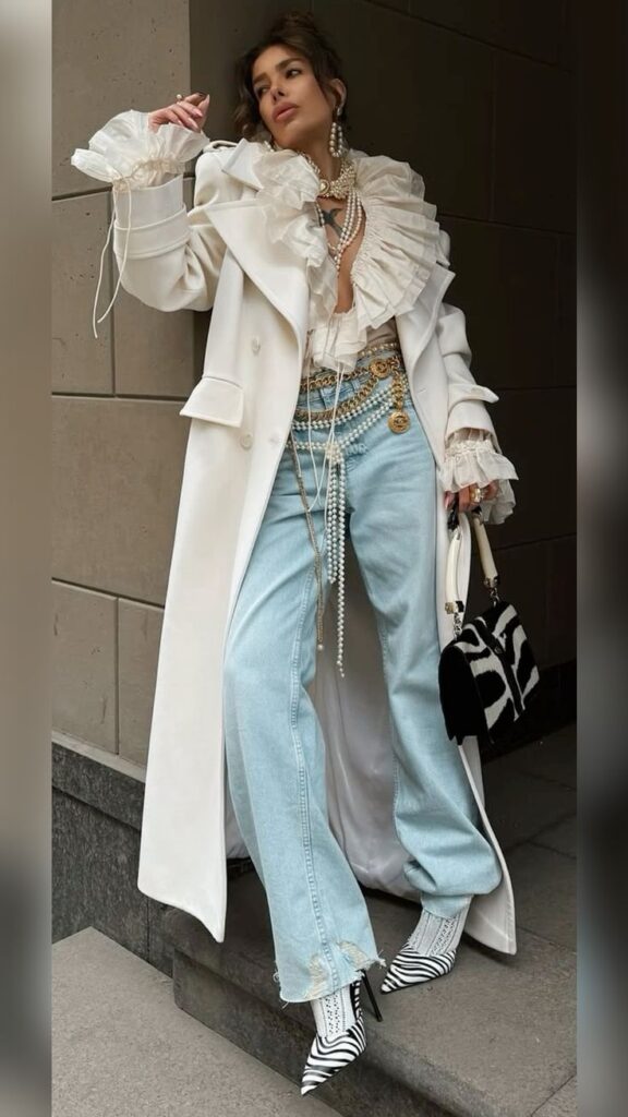 iutgkgk Woman in stylish white coat, ruffled blouse, jeans, and zebra heels, accessorized with pearls and a patterned bag. | Sky Rye Design Woman in stylish white coat, ruffled blouse, jeans, and zebra heels, accessorized with pearls and a patterned bag.