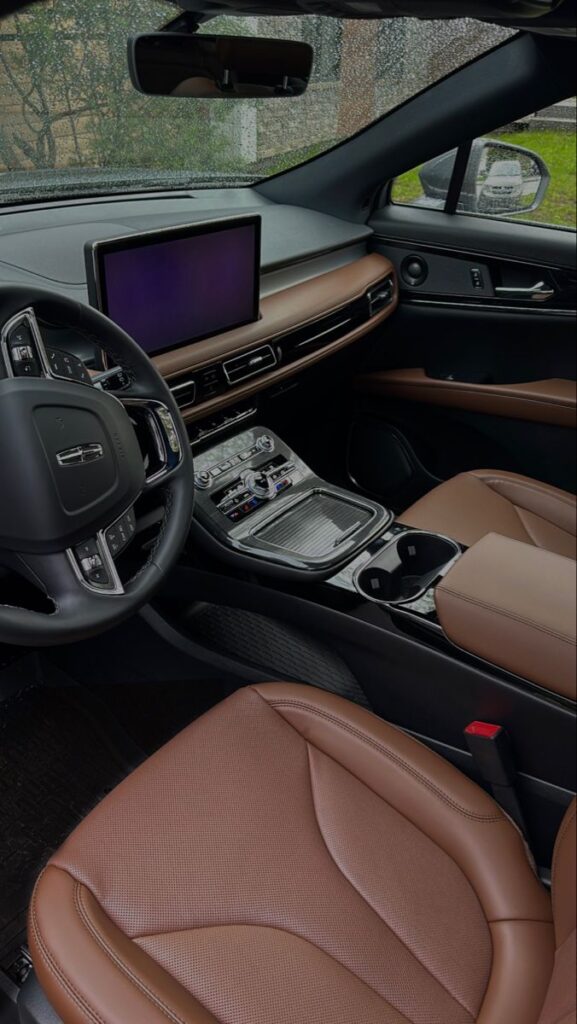 Luxury car interior with leather seats, digital dashboard, and raindrops on windshield. Modern vehicle design.
