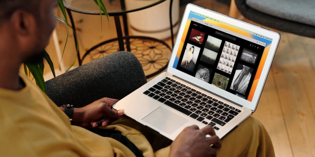 Person browsing an online photo gallery on a laptop while seated comfortably indoors.
