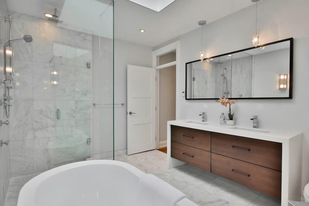 Modern bathroom with marble shower, freestanding tub, double vanity, and large mirror in a sleek, minimalist design.