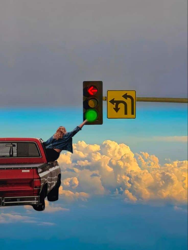 Surreal image of a person reaching for a traffic light while leaning out of a car in the clouds.