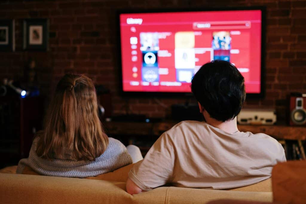 Couple watching TV on a cozy couch, entertainment selection on the screen. Perfect for home media streaming concepts.