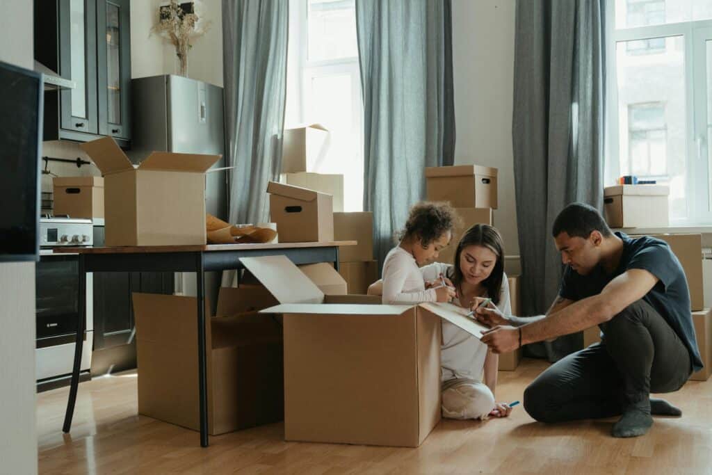 Family packing moving boxes in living room, preparing to move.