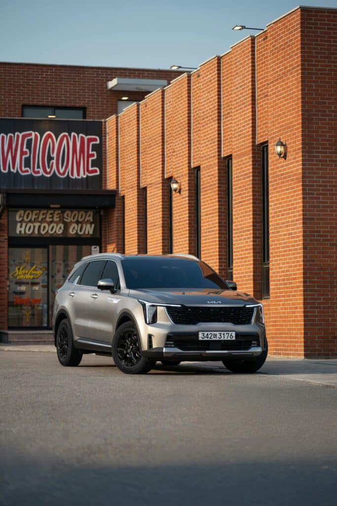 Silver SUV parked outside a brick building with a Welcome sign.