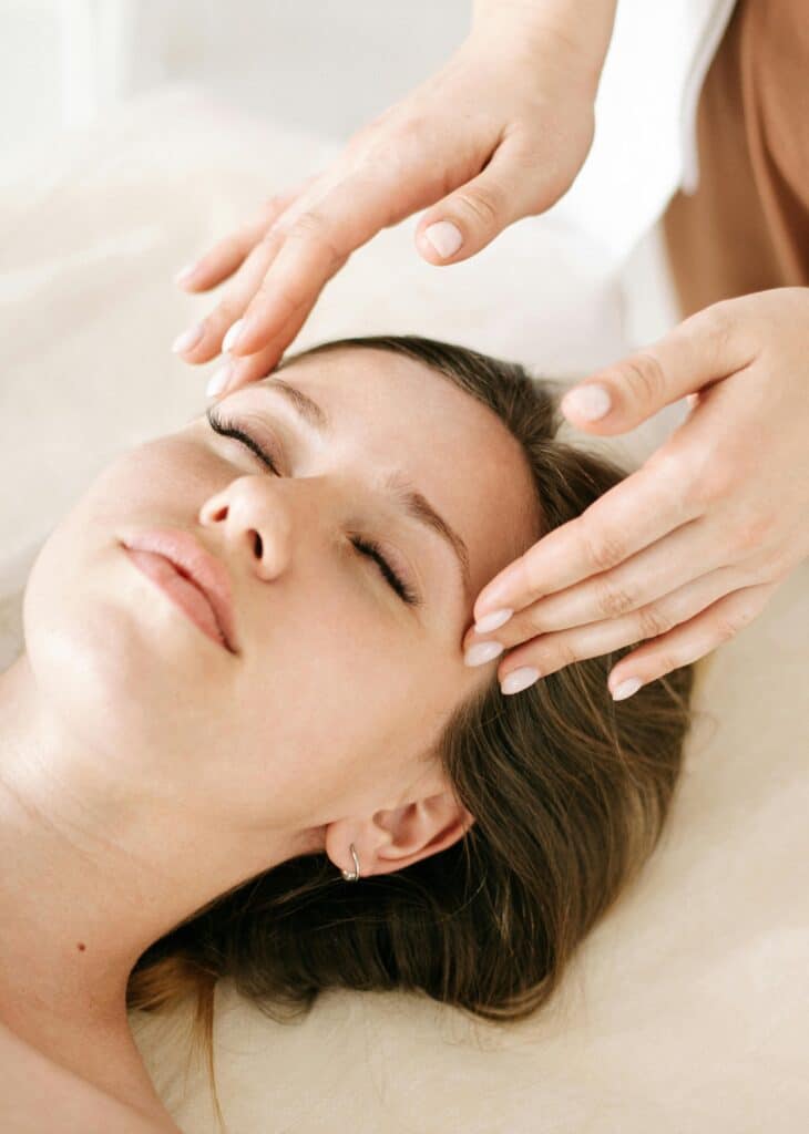 Woman receiving relaxing facial massage therapy at spa.