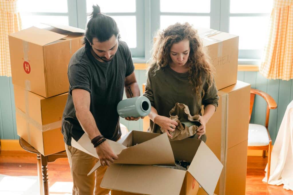 Couple unpacking boxes in new home, organizing belongings and settling in.