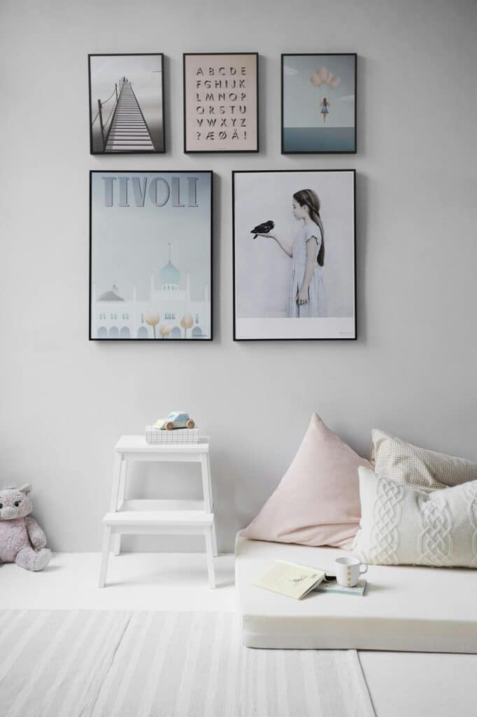 Stylish minimalistic living room with framed art, cozy cushions, and a small white step stool with a toy car.