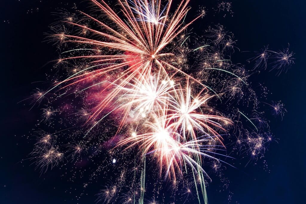 Colorful fireworks bursting against a dark sky, illuminating the night with vibrant streaks and bursts.