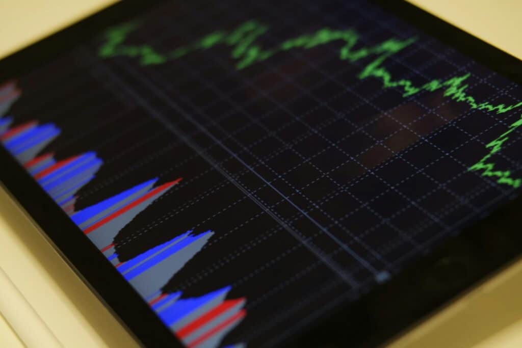 Tablet displaying colorful financial graphs and stock market data analysis in a dark setting.
