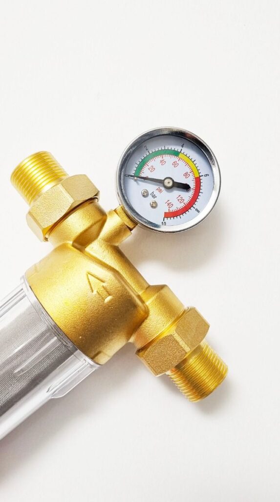 Gold water pressure gauge with filter, showing PSI and bar readings, on white background.