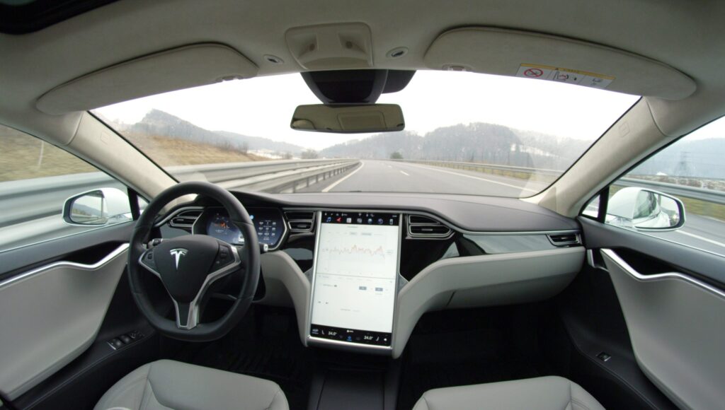 Self-driving car interior on highway, showing advanced dashboard technology and sleek modern design.