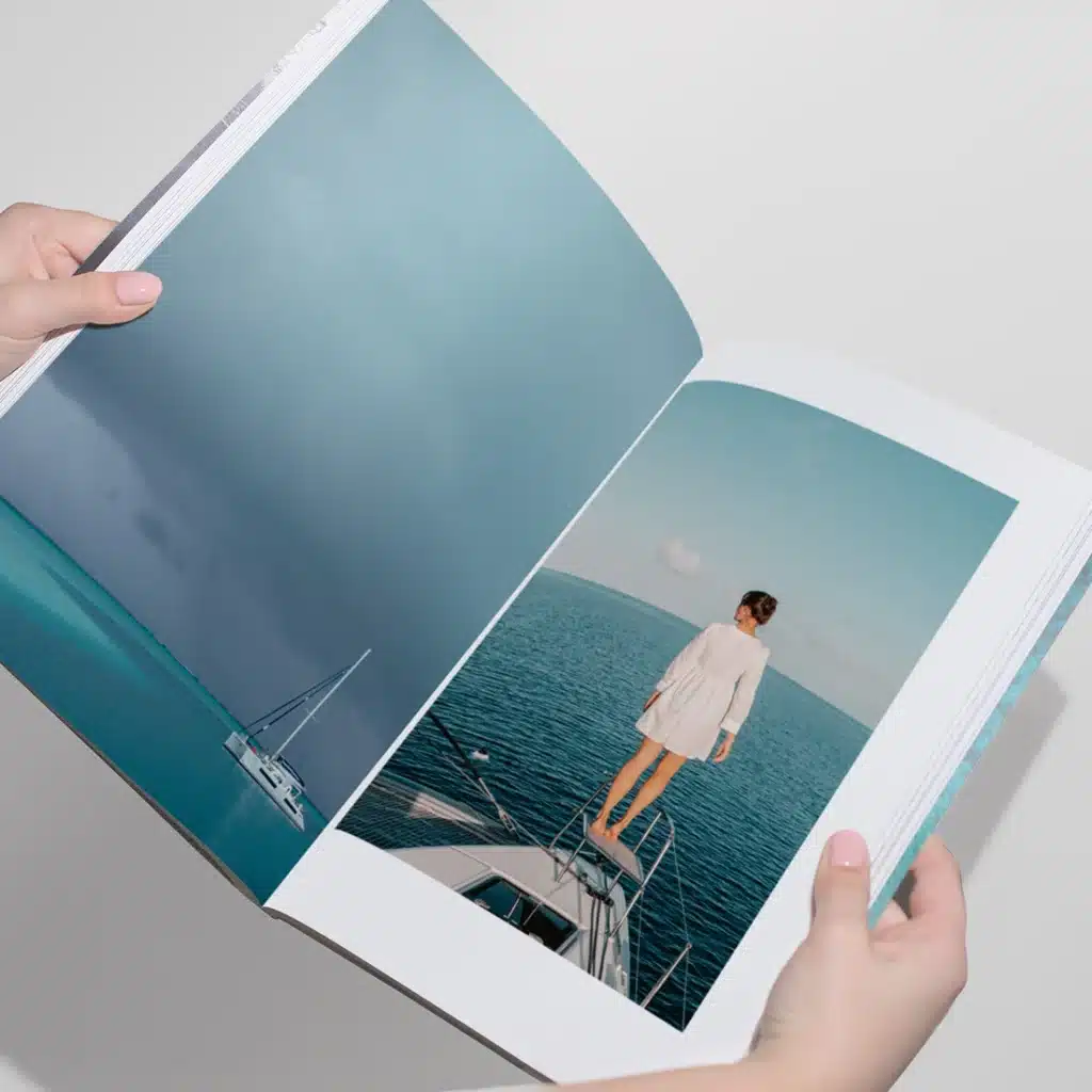 Person stands on yacht bow, overlooking vast ocean under clear skies, featured in an open book.