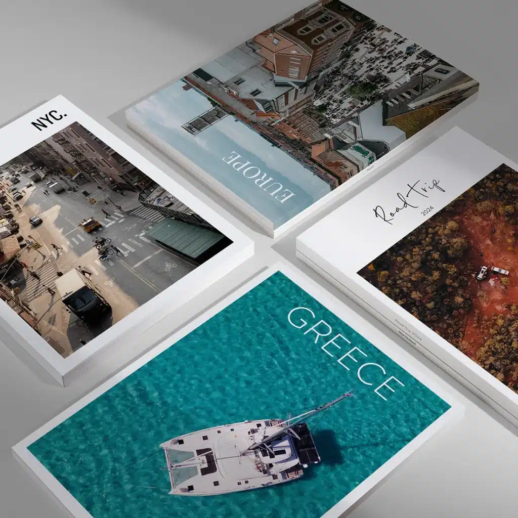 Travel photo books featuring covers of NYC, Europe, Greece, and a 2024 Road Trip, laid out on a gray surface.