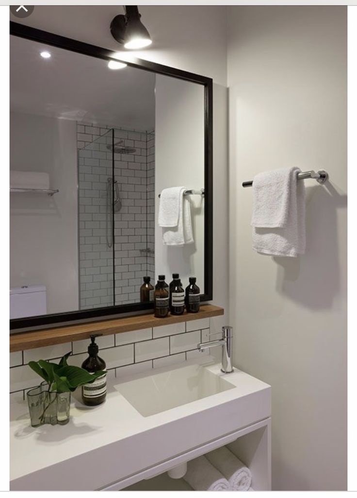Modern bathroom with sleek vanity, large mirror, and stylish subway tile shower. White towels and toiletries add elegance.