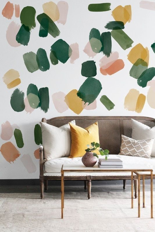 Stylish living room with abstract green and mustard wall art, beige sofa, and decorative pillows.