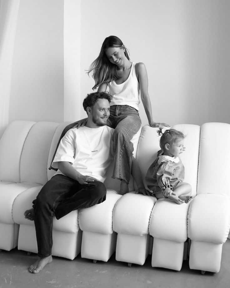 Family sitting on a white sofa, smiling and spending quality time together in a cozy living room.