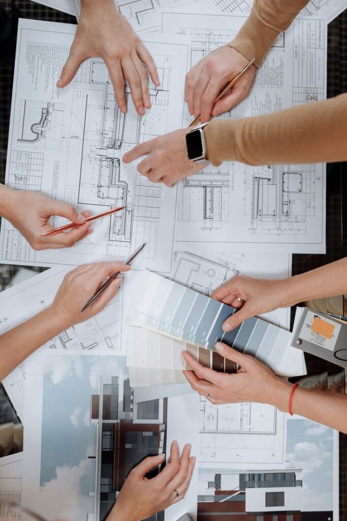 Architects discussing blueprints and color palettes at a table, collaborating on design plans.