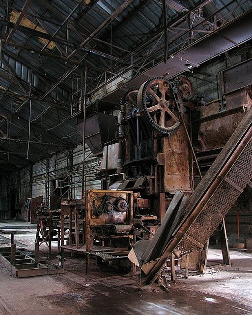 Abandoned industrial machinery in a dimly lit factory with metal beams and rustic textures.