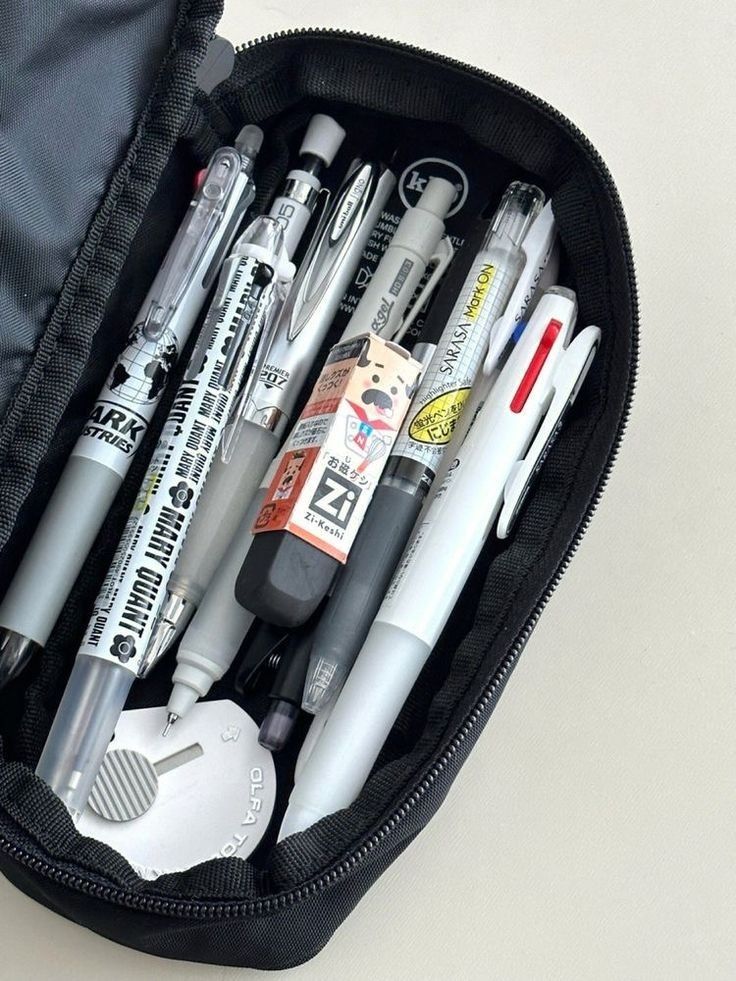 Open pencil case with various pens, mechanical pencils, and erasers, arranged neatly for school or office use.