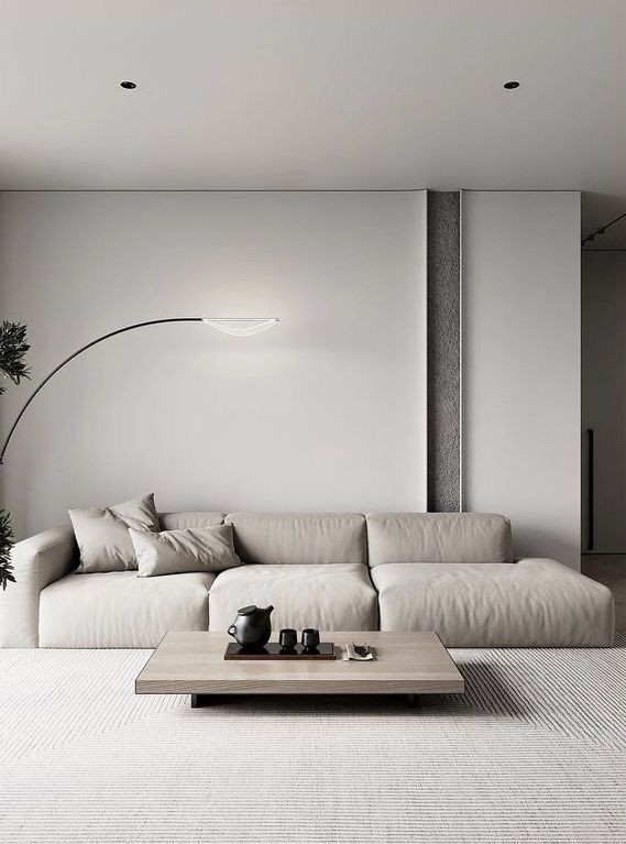 Modern minimalist living room with beige sofa, sleek coffee table, and stylish floor lamp.