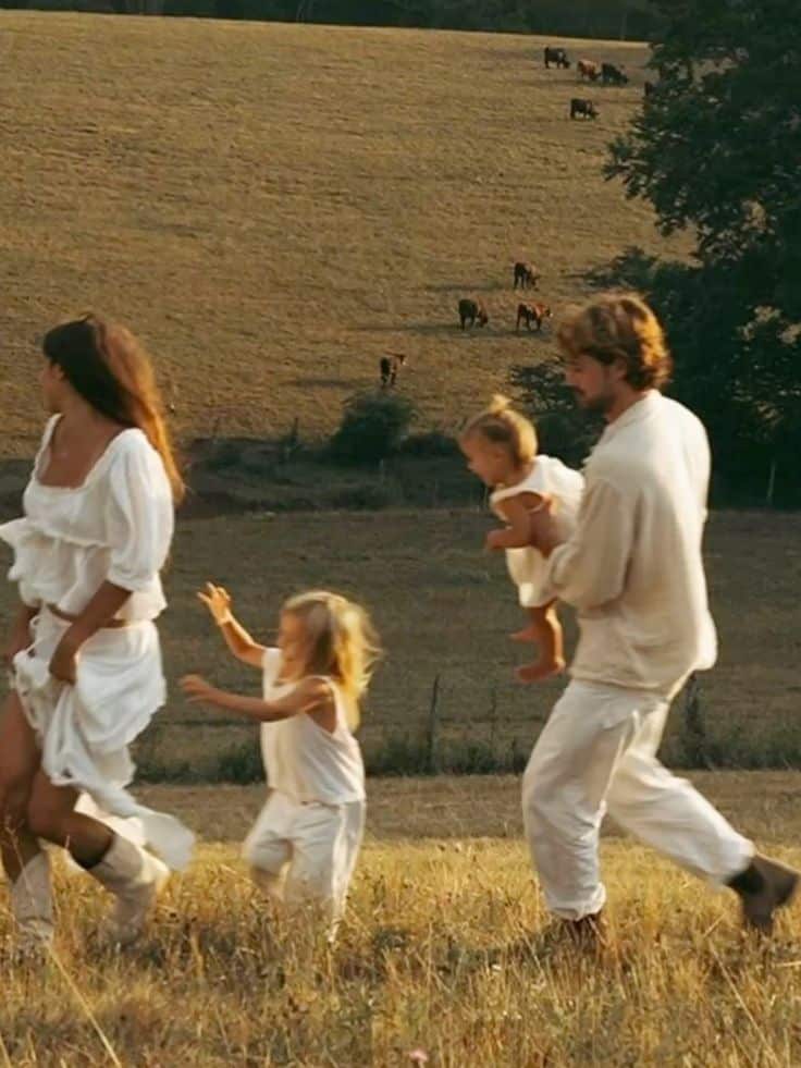 Family enjoying a summer day in a scenic field with cows in the background.