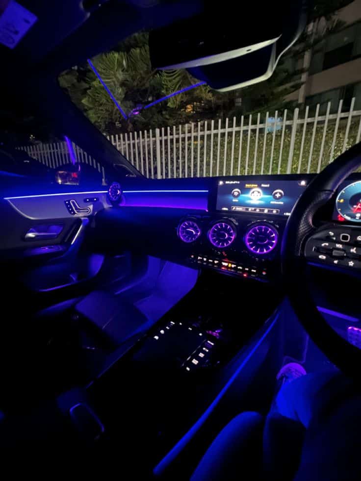 Luxury car interior with ambient blue lighting and digital console at night.