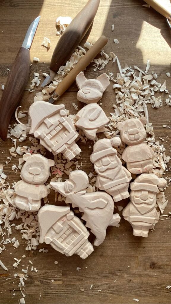 Деревянные елочные игрушки https___vk_com_id710149559 Wood carving of various figures surrounded by shavings and carving tools on a wooden table. | Sky Rye Design Wood carving of various figures surrounded by shavings and carving tools on a wooden table.