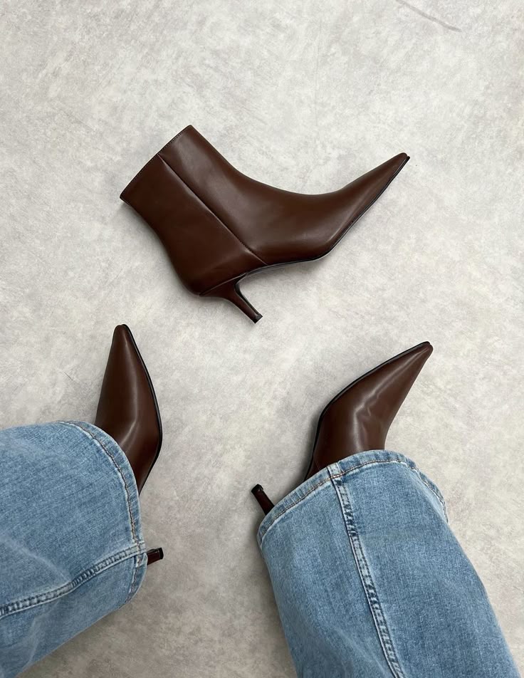 Brown leather ankle boots paired with blue jeans on a light background. Fashion footwear style.