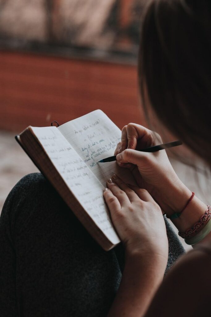 Person writing in a notebook, focusing on journaling or creative writing in a cozy setting.