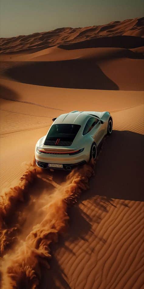 Sports car driving through desert sand dunes, creating a dramatic trail.