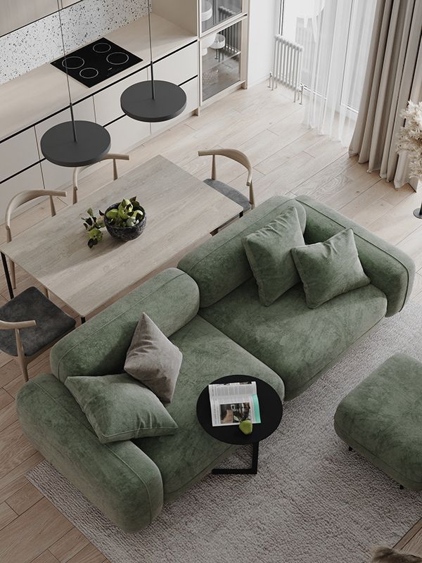 Modern living room with green sofa, wooden dining table, and minimalist kitchen design.