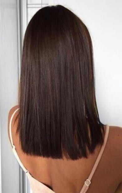 Woman with sleek, straight brown bob haircut, viewed from the back, wearing a beige top with thin straps.