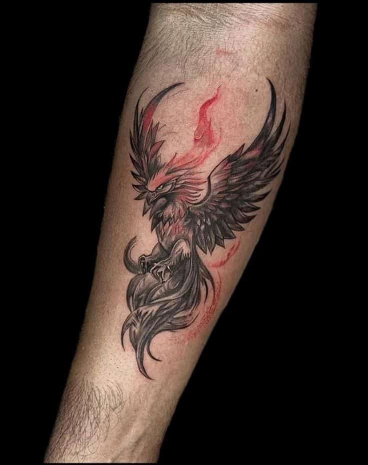 Phoenix tattoo in black and red ink on forearm, symbolizing rebirth and strength.