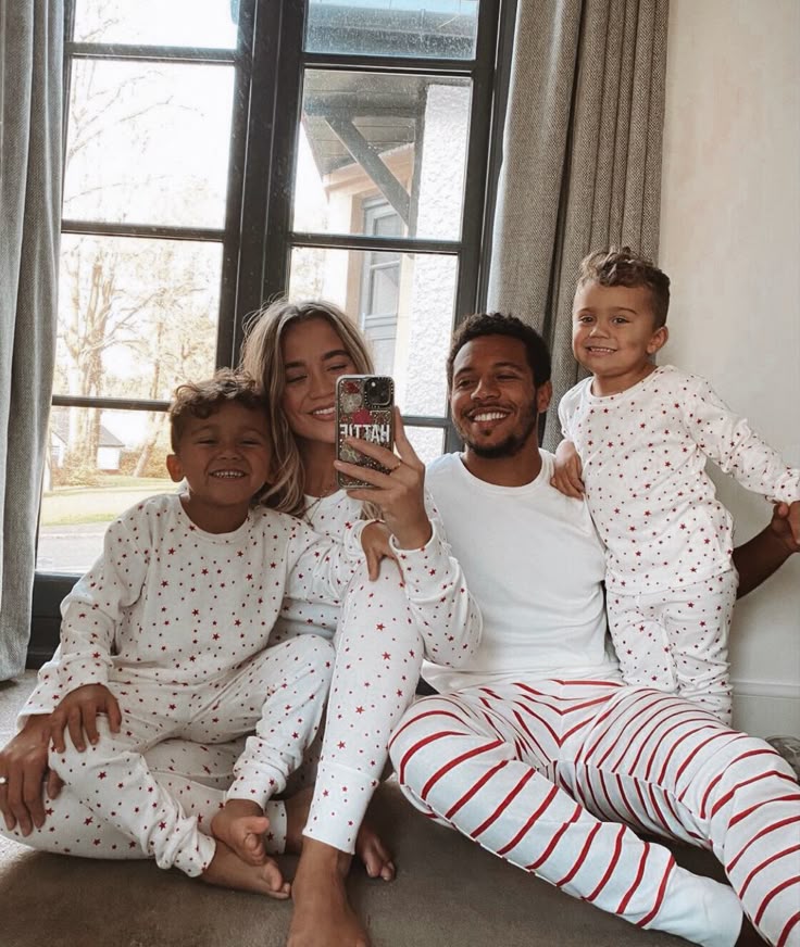 Family in matching pajamas taking a happy selfie by the window, enjoying cozy time together.