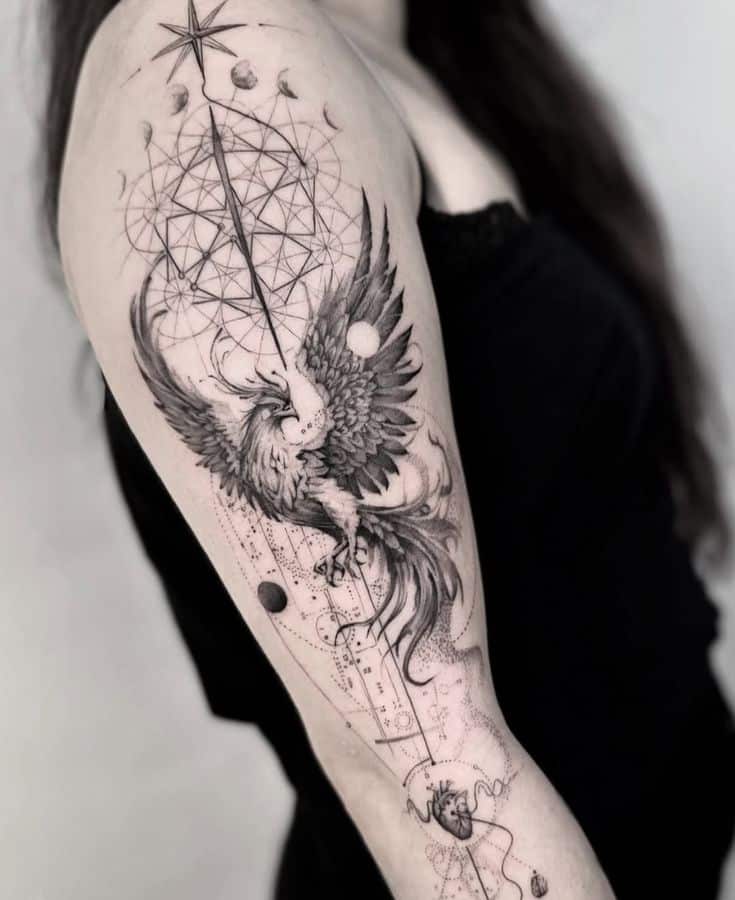 Intricate black and grey phoenix tattoo on arm with geometric patterns and celestial symbols.