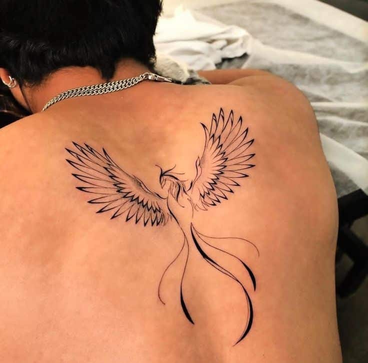 Phoenix tattoo design on a person's back with outstretched wings, symbolizing rebirth and strength.