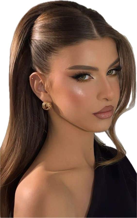 Woman with sleek ponytail, glamorous makeup, and gold earrings, wearing an off-shoulder black top.