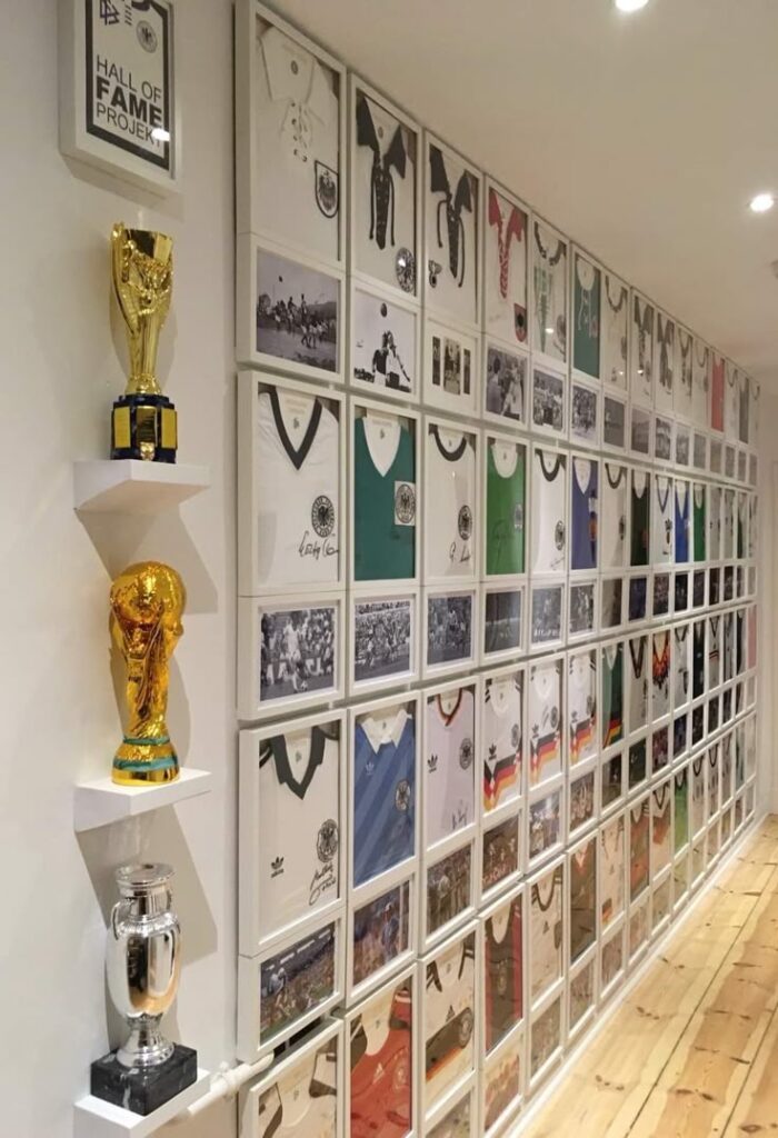Wall of framed soccer jerseys and trophies in a sports hall of fame exhibit.
