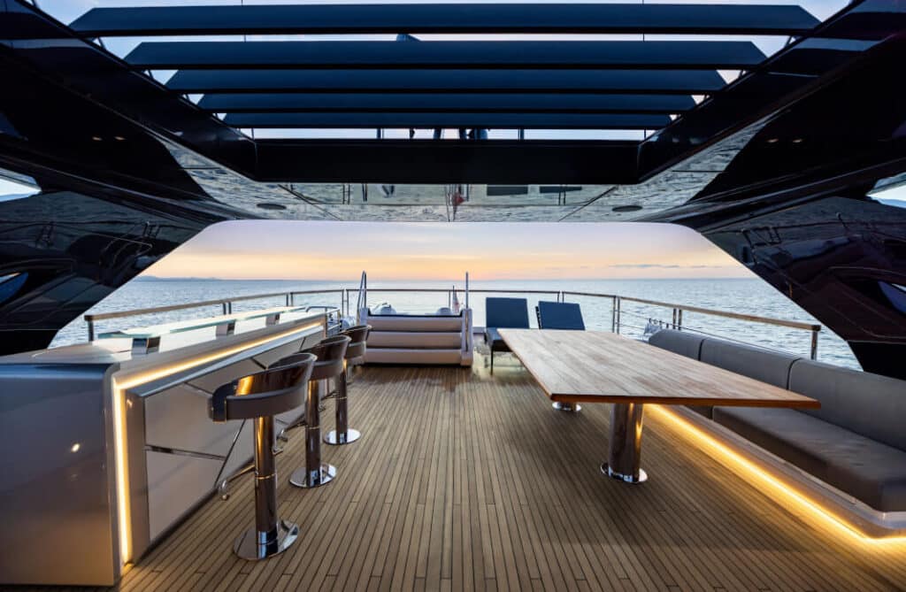 100-Yacht-Exterior Luxury yacht deck with bar and table, offering a stunning sunset ocean view. | Sky Rye Design Luxury yacht deck with bar and table, offering a stunning sunset ocean view.