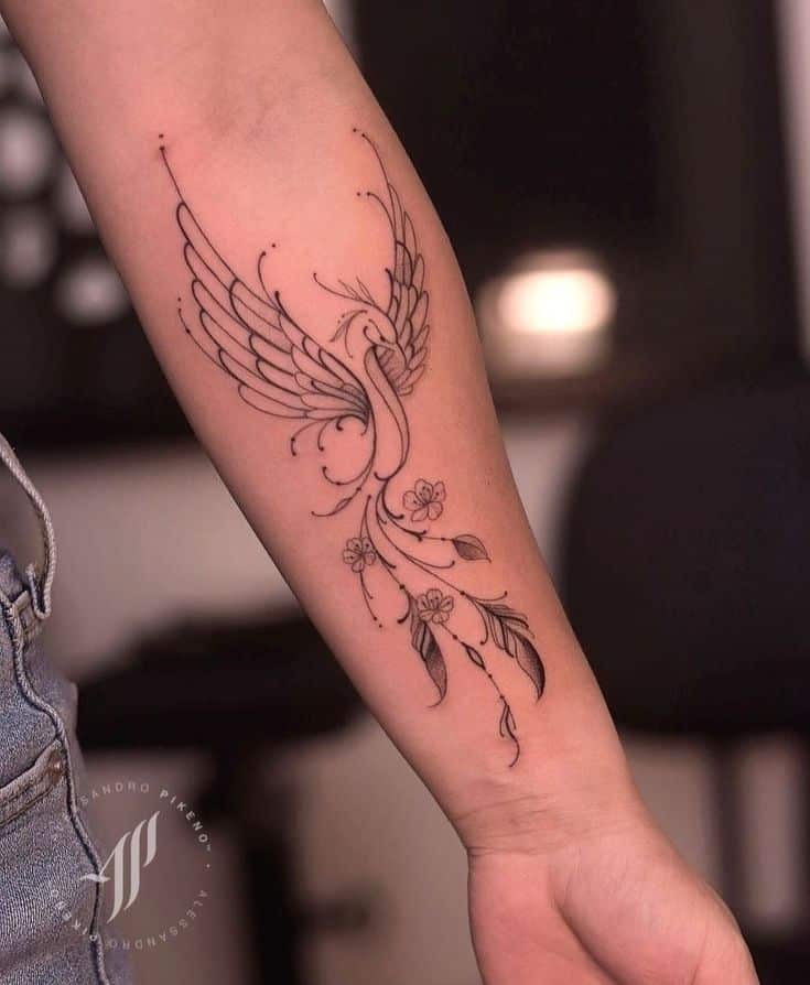 Elegant phoenix tattoo with floral design on forearm.