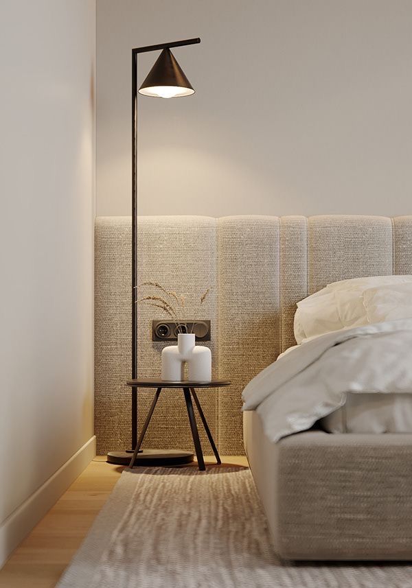 Modern bedroom with a stylish floor lamp, textured headboard, and minimalist side table for cozy ambiance.