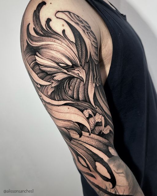 Detailed black and gray eagle tattoo on upper arm, featuring intricate feather design and bold shading.